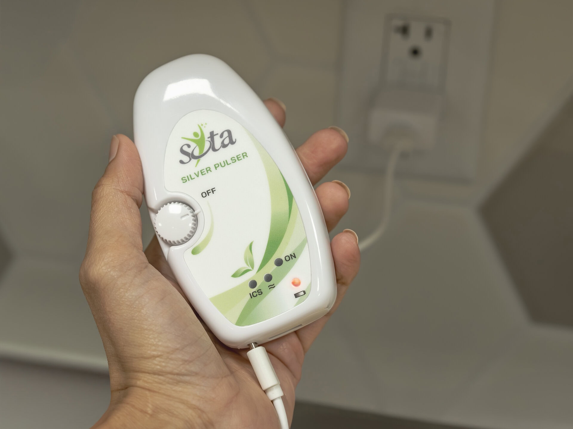 A hand holding the SOTA Silver Pulser unit